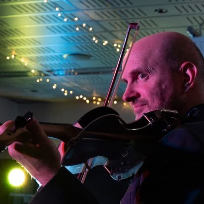 Julian Ferraretto performing, close up under string lights